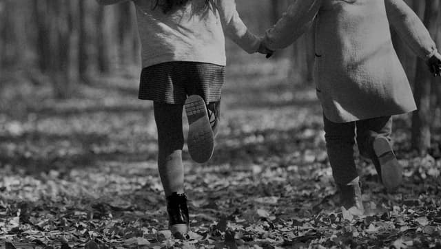 A couple, holding hands, runs down the path.