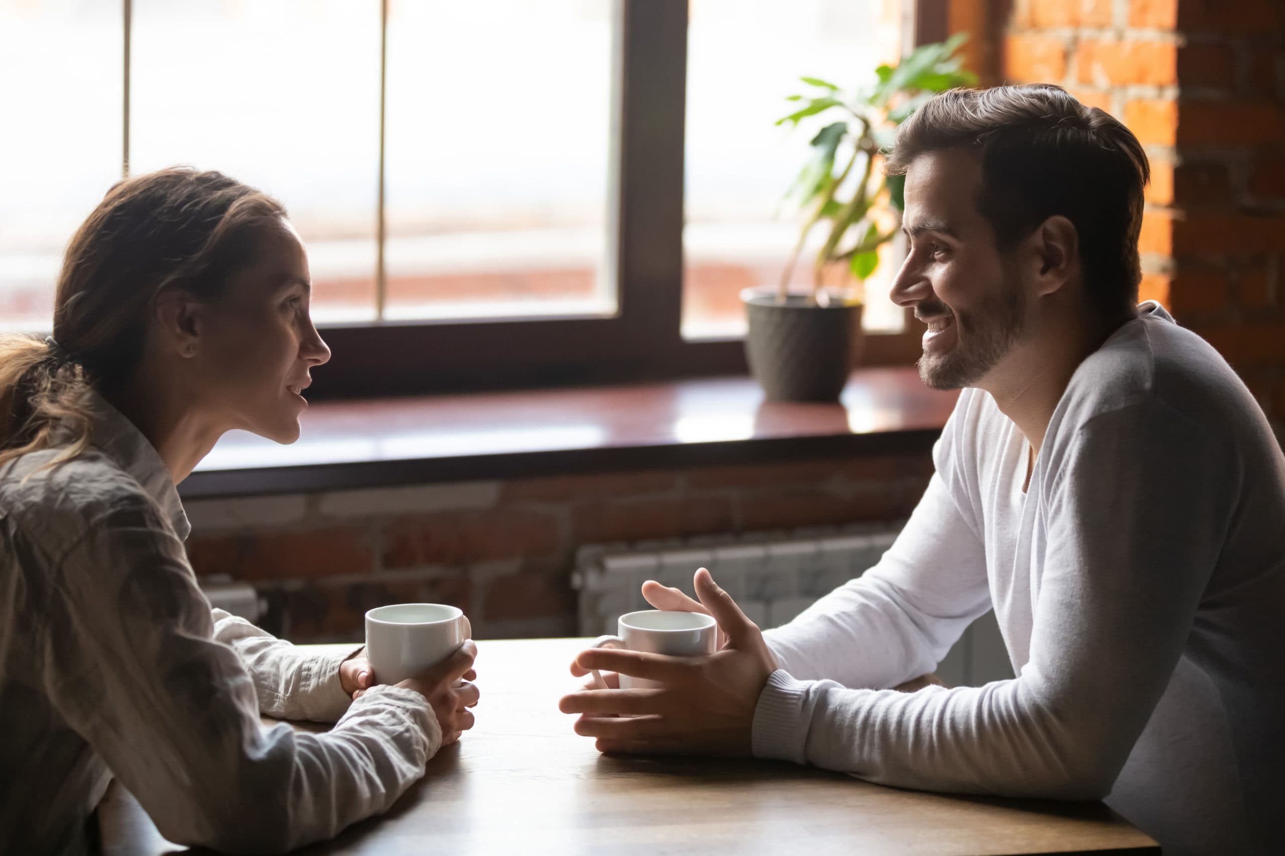 Couple sitting in cafe talking drinking tea or coffee