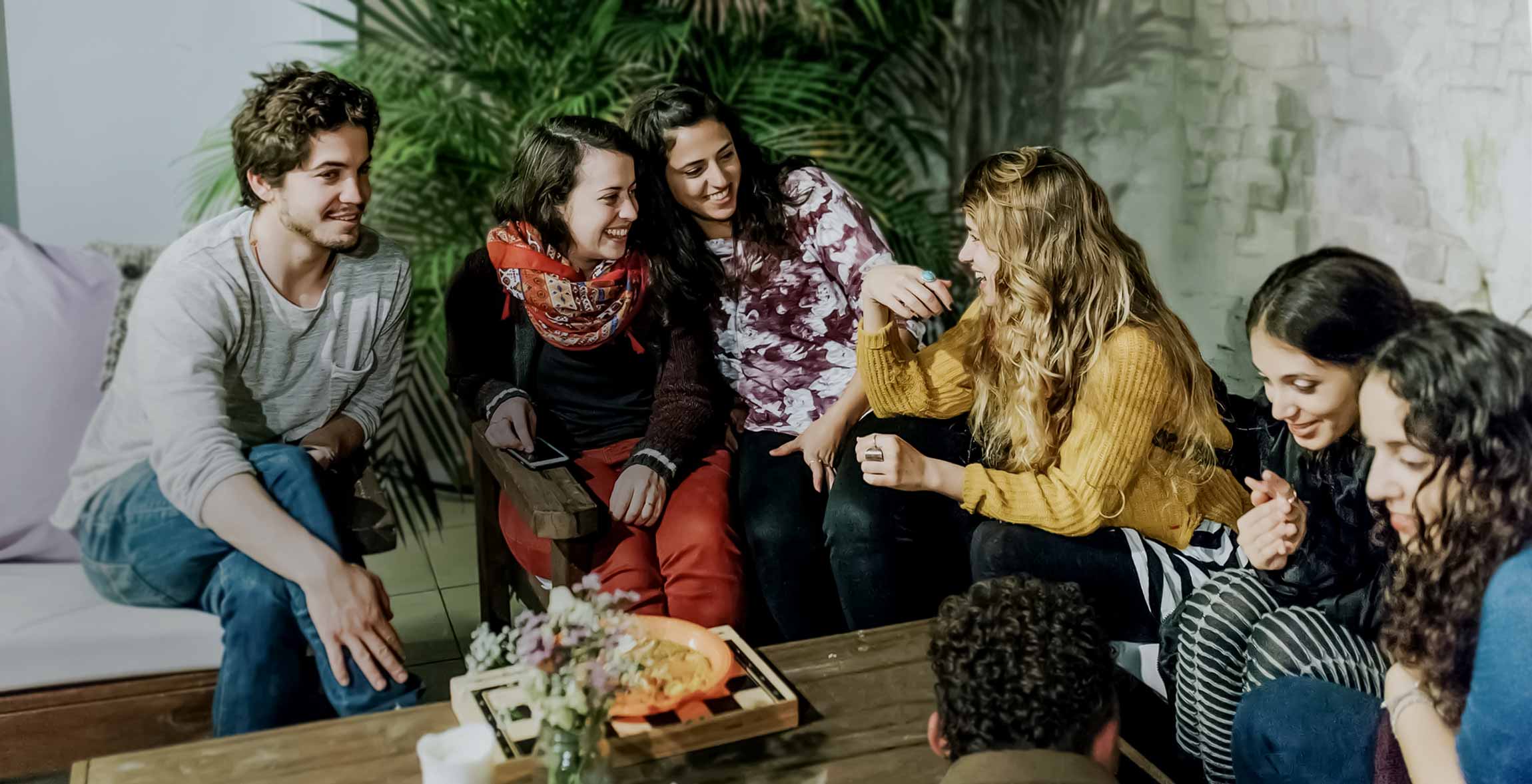Diverse group of young adults laughing and talking together in a bright indoor gathering space.
