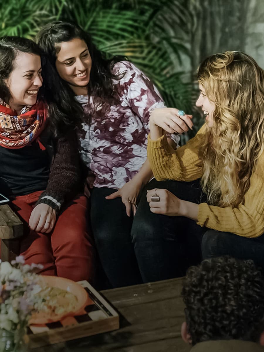 Diverse group of young adults laughing and talking together in a bright indoor gathering space.