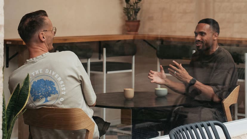 Two men are talking in a coffee shop behind a large window in Israel.