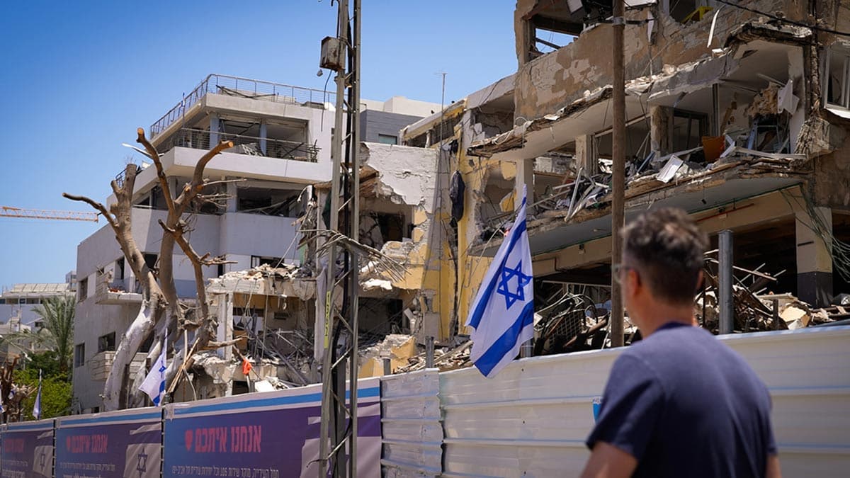 Aaron Abramson walking in the streets of Tel Aviv Israel next to destroyed buildings.