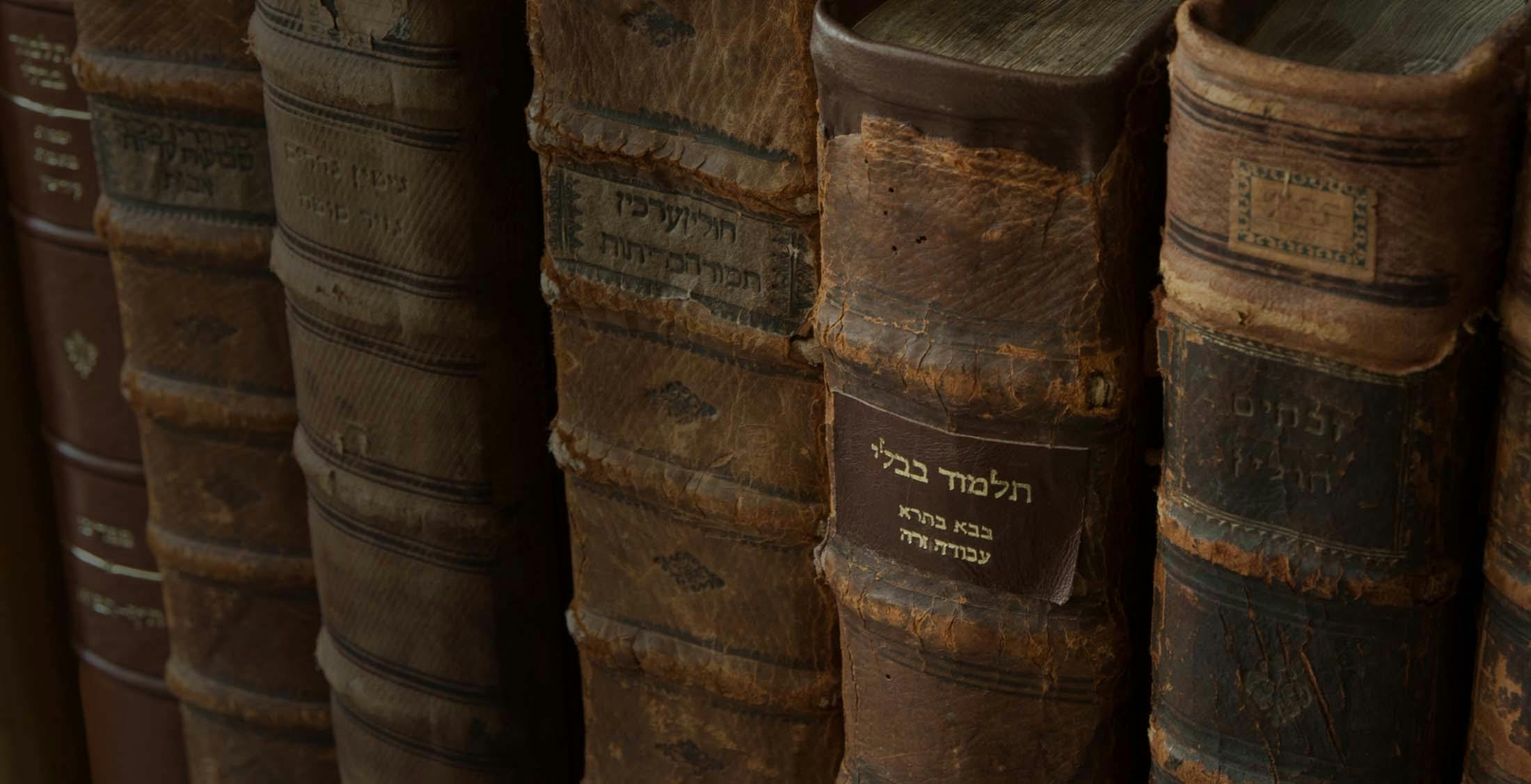 An old copy of the Talmud on a shelf with other Jewish books